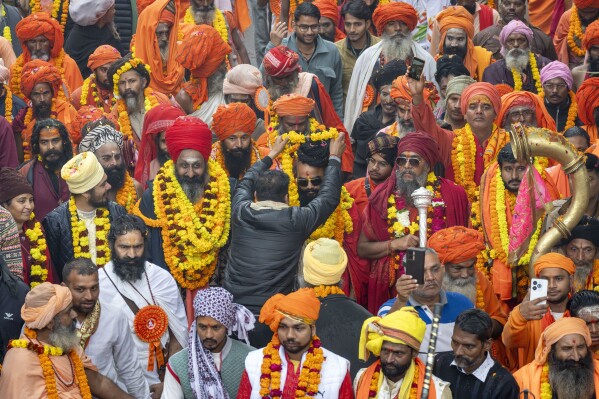 A devotee garlands a senior Hindu holy man walking in a procession, a day before the 45-day-long Maha Kumbh festival, in Prayagraj, India, Sunday, Jan. 12, 2025. (AP Photo/Ashwini Bhatia)